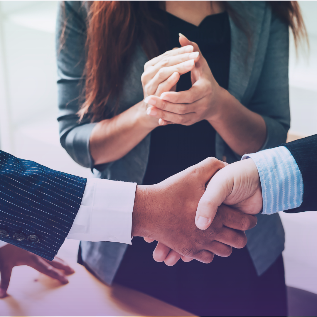 Business professionals shake hands while another claps, symbolizing strong partnerships for supply chain excellence.