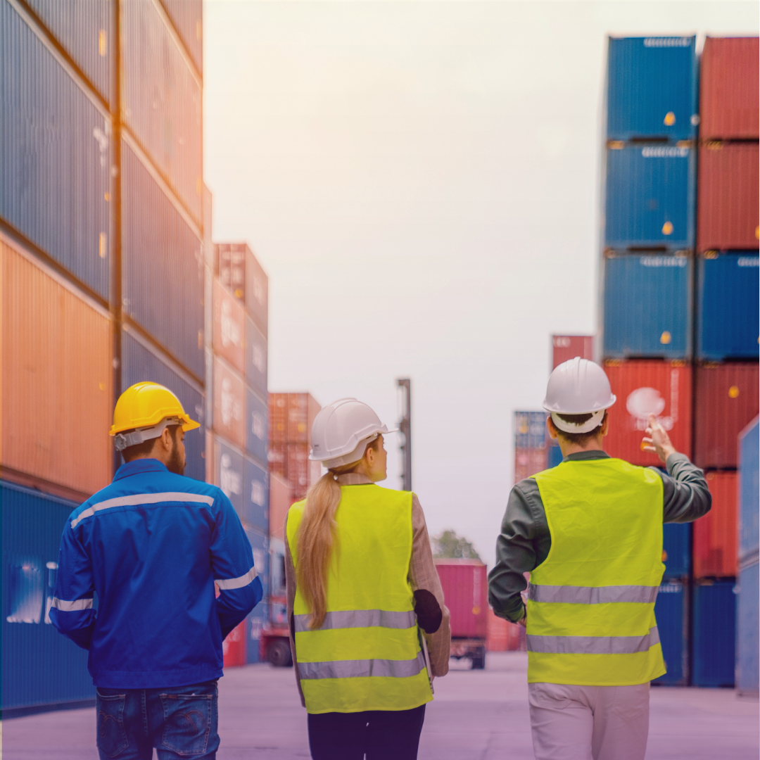 Logistics professionals in safety gear walk through a container yard, symbolizing global supply chain expansion.