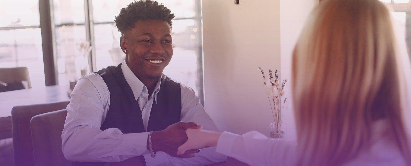 Smiling man in a collared shirt shakes hands, symbolizing a new career opportunity.