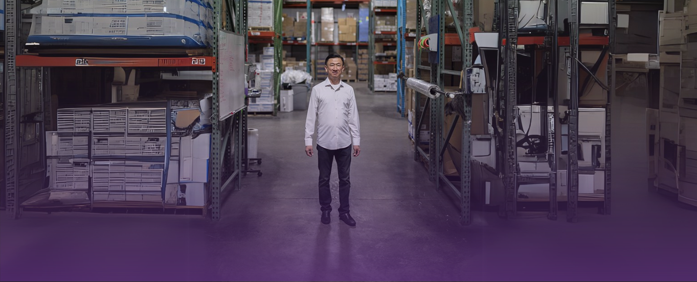 AOSS Medical Supply CEO Eric Liew smiles in a warehouse aisle with medical supplies, symbolizing supply chain leadership.