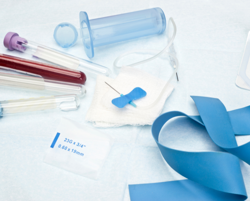 Close-up of phlebotomy medical supplies: blood collection tubes, butterfly needle, tourniquet, and needle holder.
