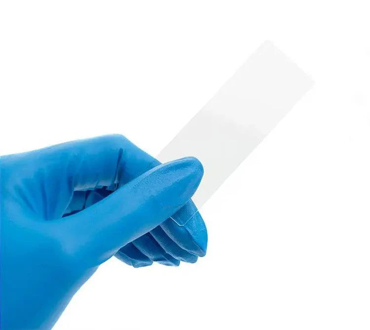 Blue-gloved hand holding a white plastic tool against a white background