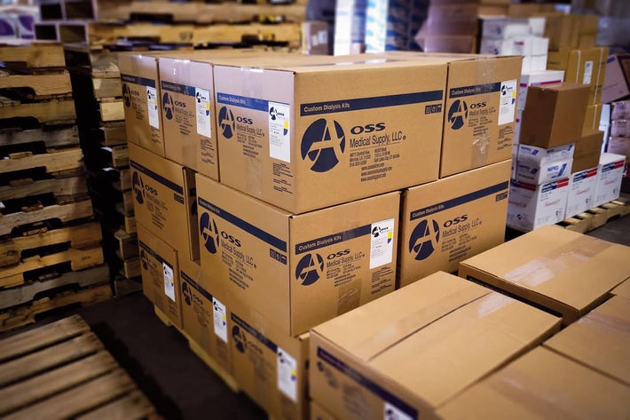 Stacked boxes of 'AOSS Medical Supply, LLC' custom dialysis kits on pallets in a warehouse, ready for distribution.
