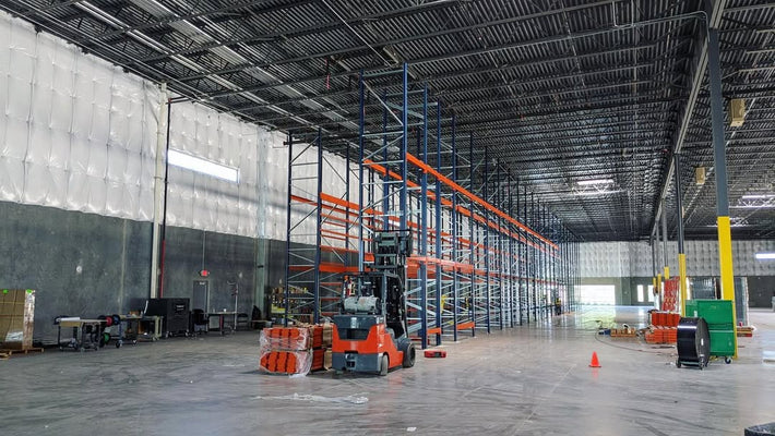 Spacious, empty warehouse interior with high ceilings, new pallet racking, and a forklift, ready for inventory and logistics operations.