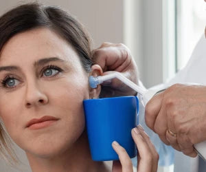 Person receiving an ear examination with a blue ear canal mirror.